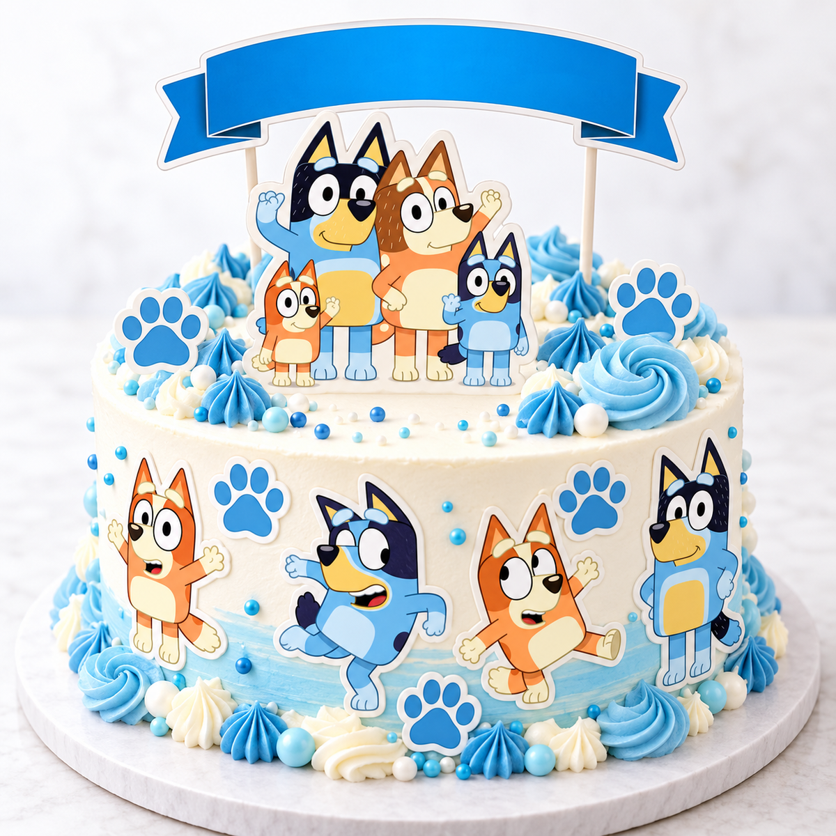 White birthday cake decorated with Bluey family edible toppers, blue paw prints, a blank blue banner and blue piped swirls.