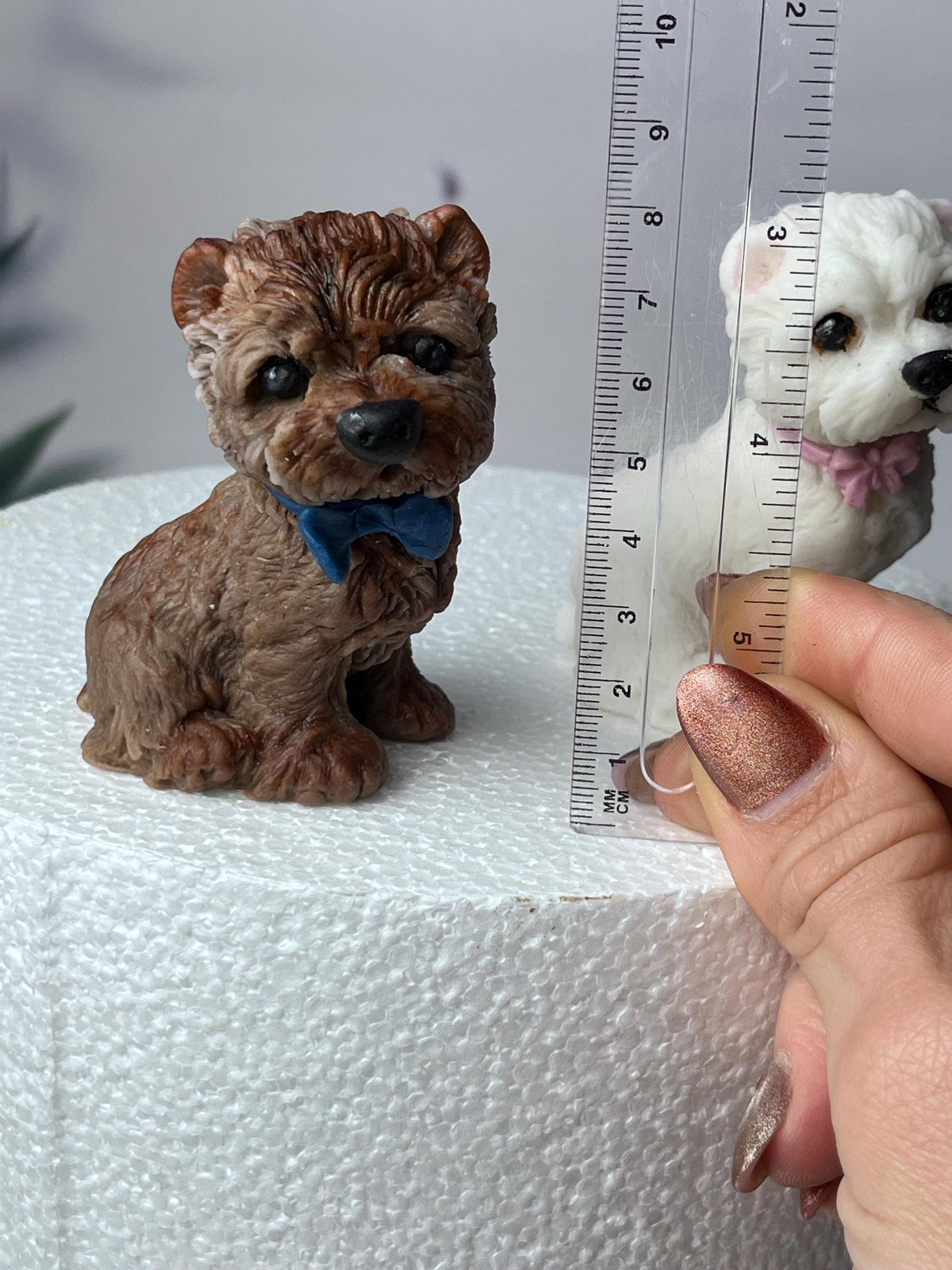 Brown edible fondant terrier dog cake topper beside a ruler showing its height.