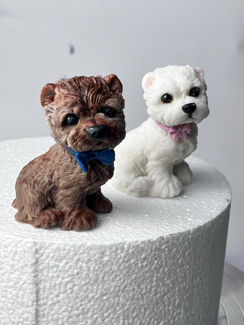 Brown and white edible fondant terrier dog cake toppers with blue and pink bows.