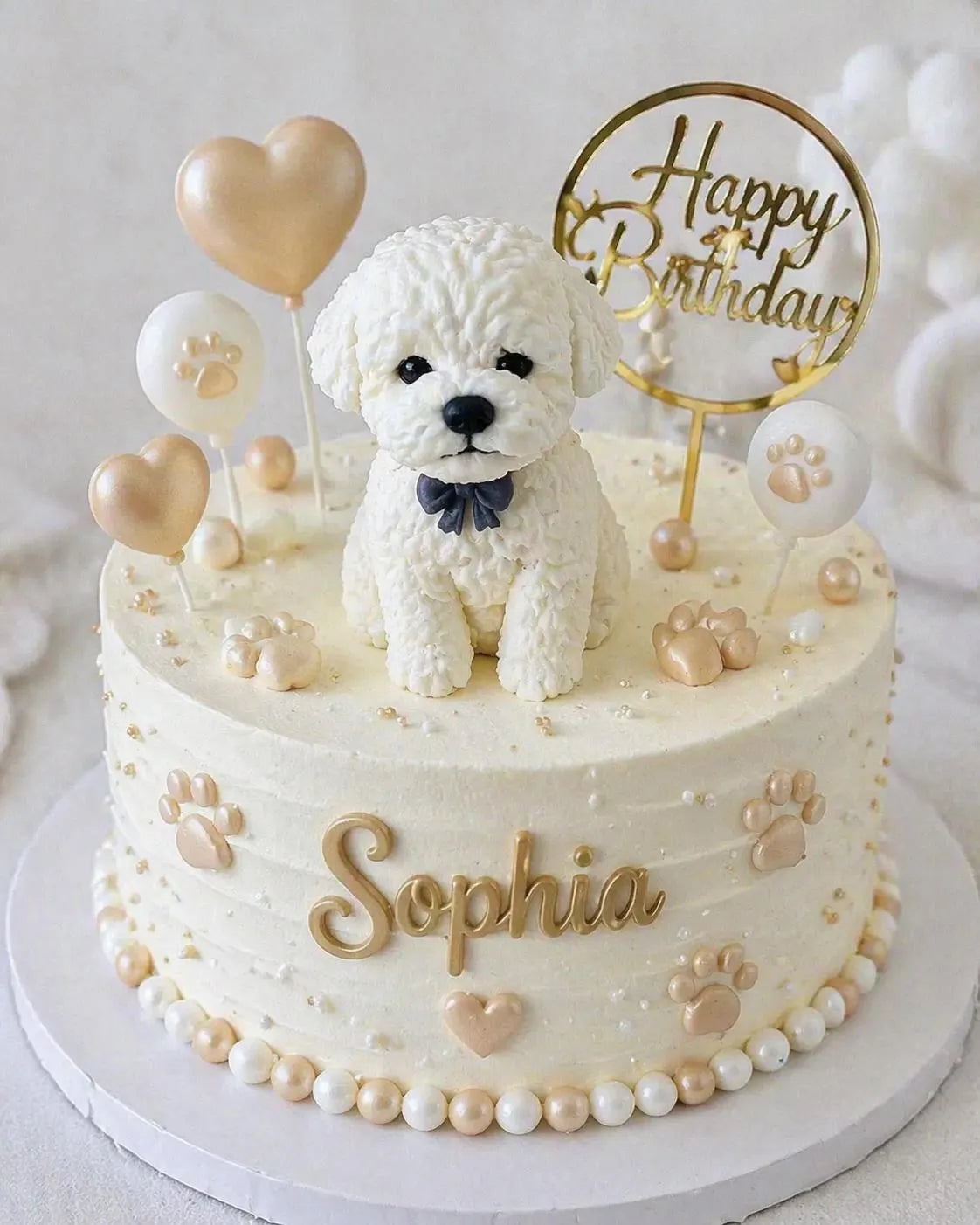 White edible fondant dog cake topper with textured fur and a dark bow, displayed on a birthday cake.