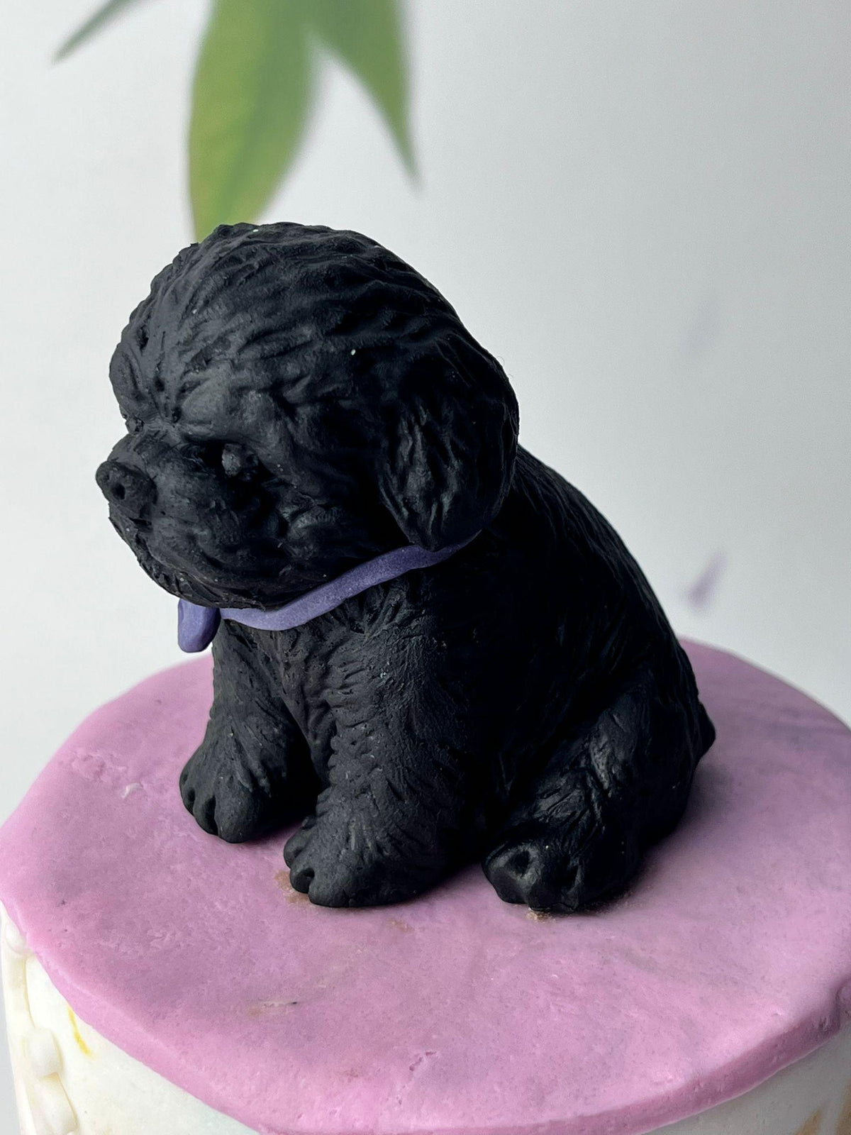 Black handmade edible fondant dog cake topper with textured fur and a purple collar.
