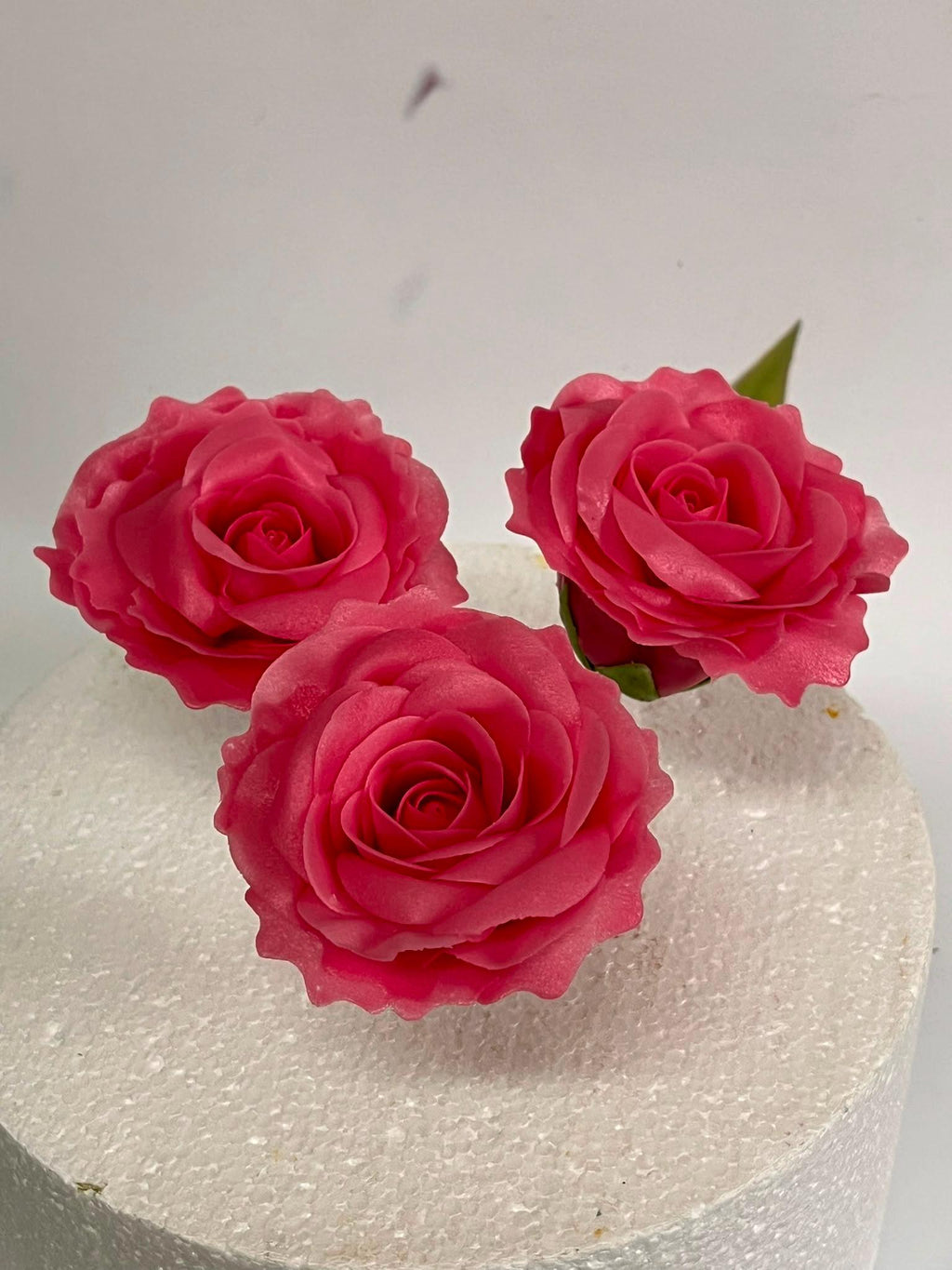 Three red handmade edible sugar roses for cake decoration.