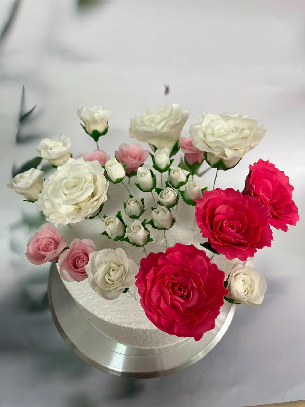 Red, ivory and pink handmade sugar roses arranged on a cake.