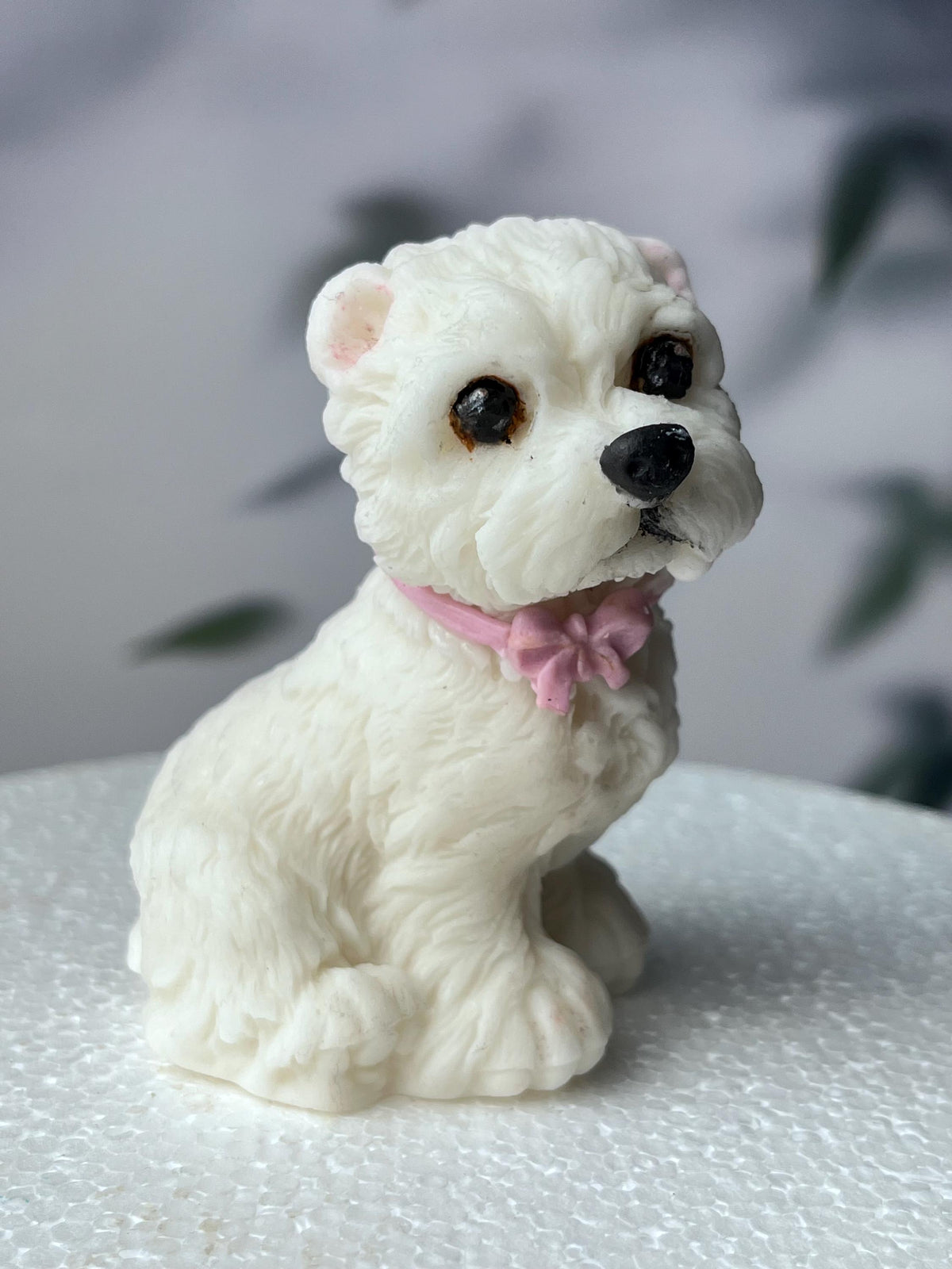 White edible fondant terrier dog cake topper with a pink bow, front view.