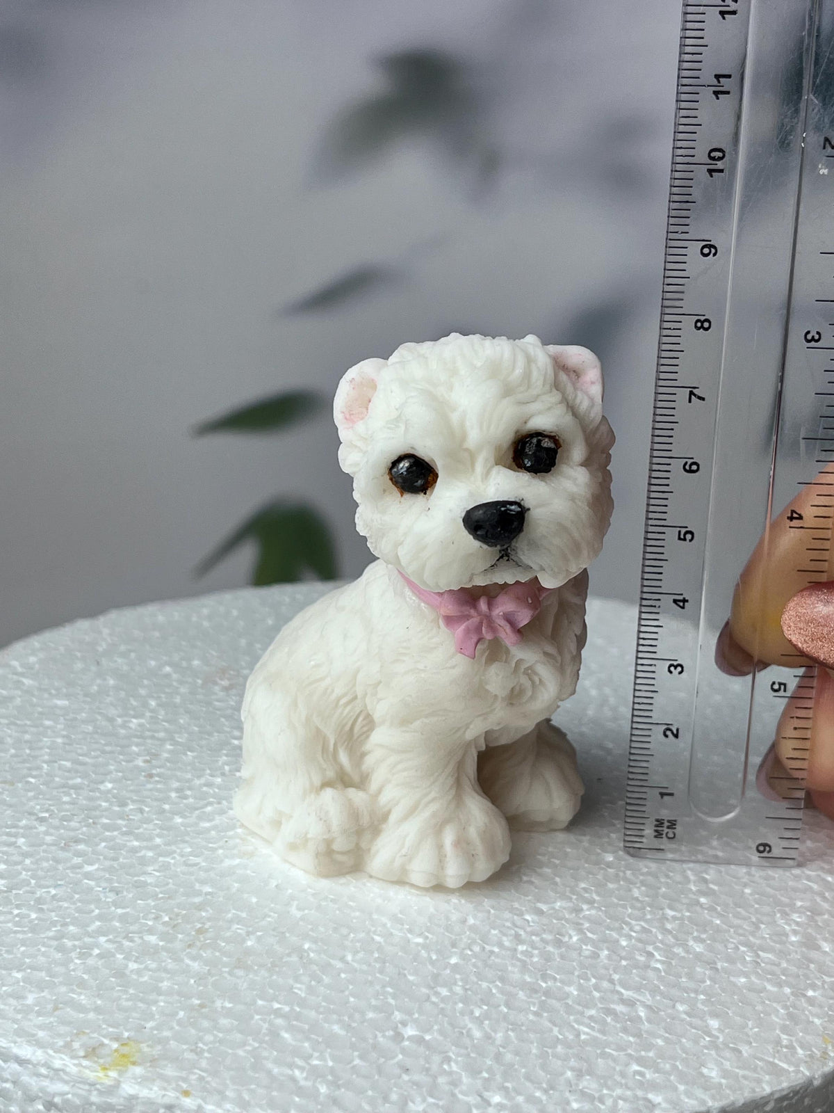 White edible fondant terrier dog cake topper beside a ruler showing its height.