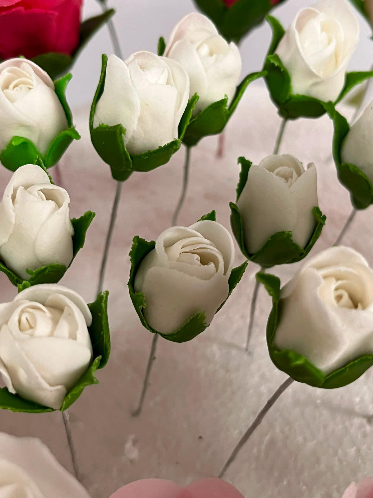 White sugar rosebuds with green leaves for wedding cake decoration.