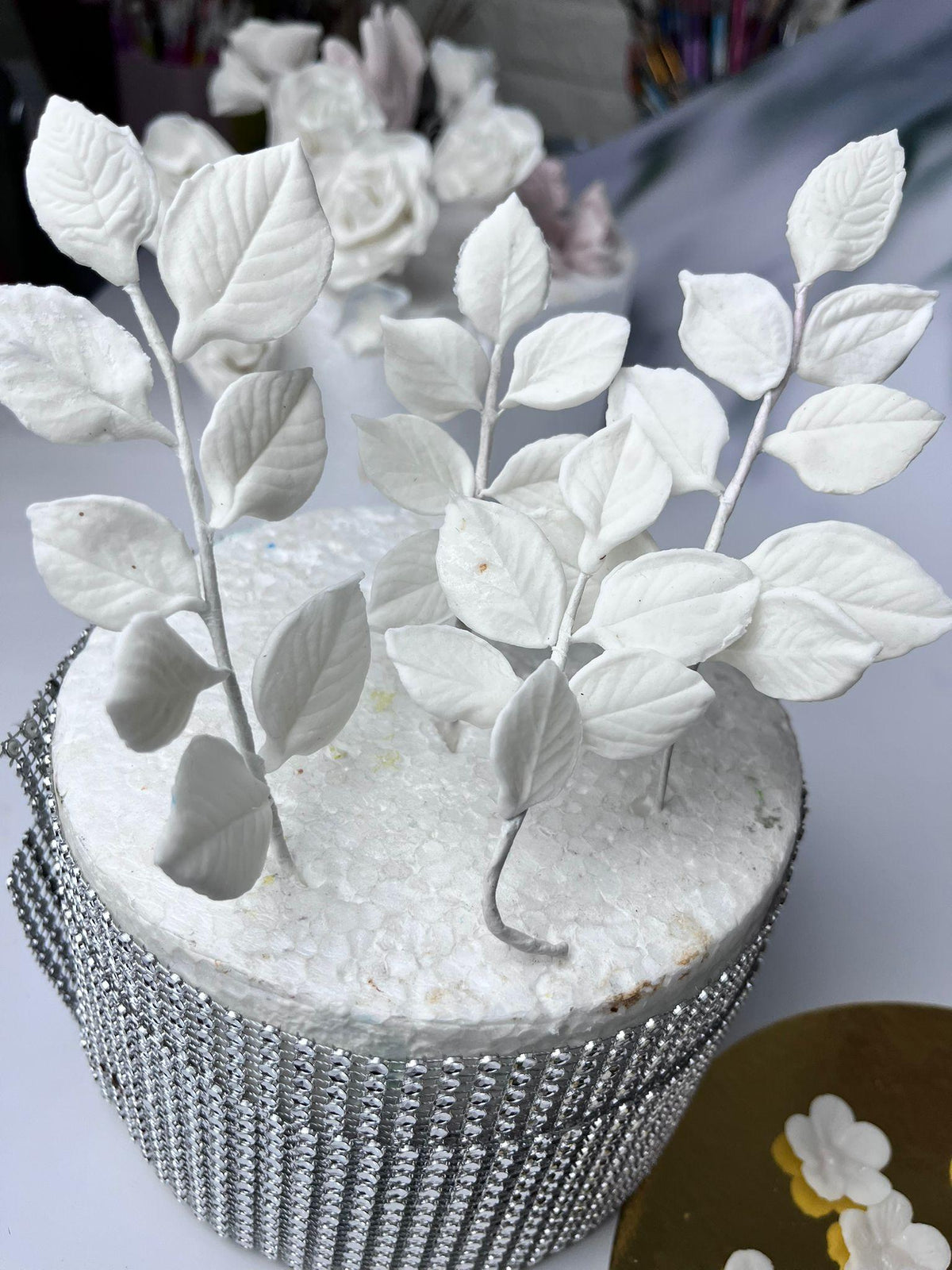 White sugar roses, rosebuds and leaf branches for cake decorating.
