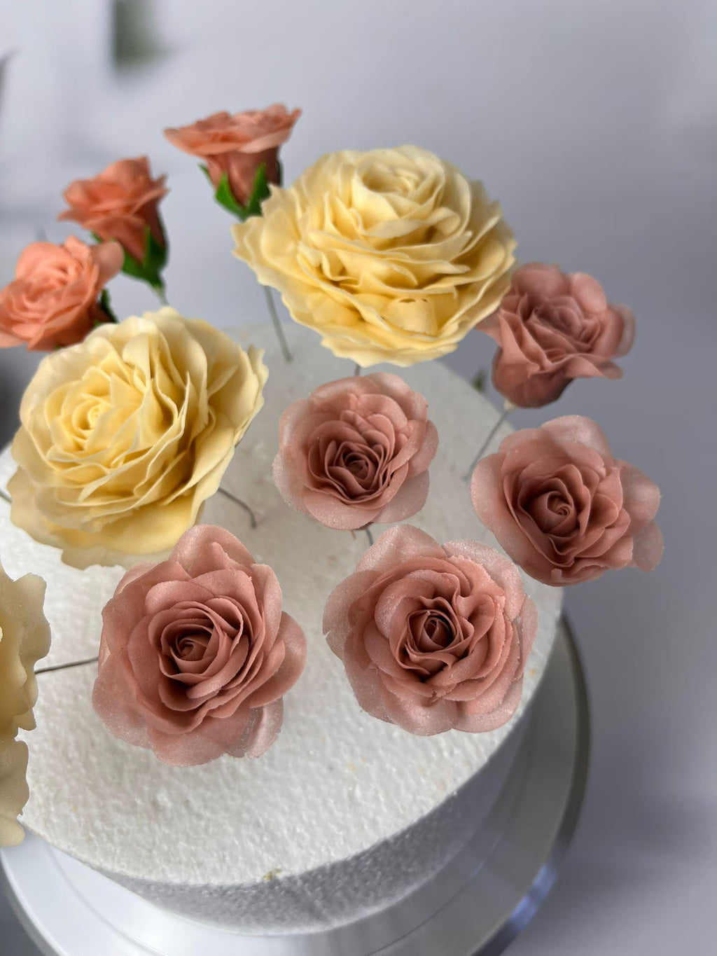 Handmade yellow and dusty pink sugar roses on a celebration cake.