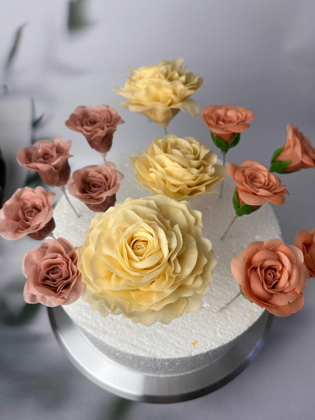Yellow and peach sugar roses with green leaves on a celebration cake.